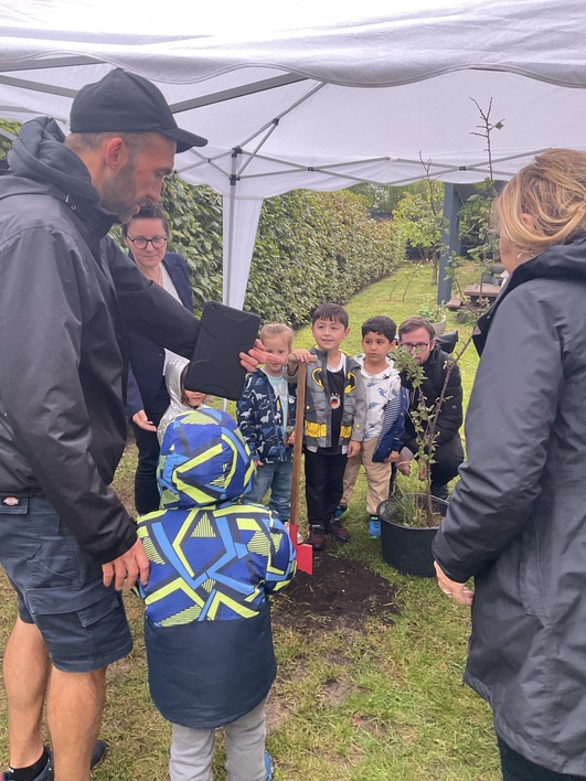 Die Kinder lernen wie man einen Baum pflanzt